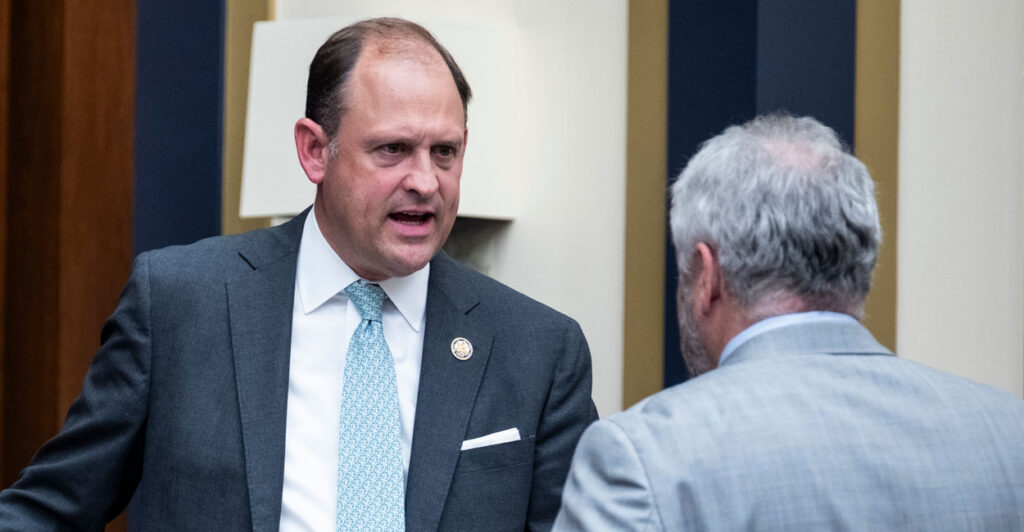 Rep. Andy Barr, R-Ky., speaks with Rep. Warren Davidson, R-Ohio, before a hearing. Both men are standing and Barr has a dark suit on and Davidson has a light grey suit on.