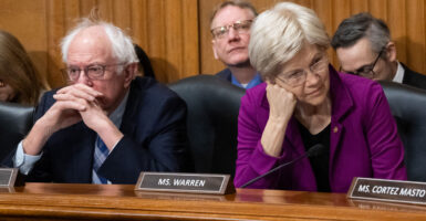 Bernie Sanders, with his hands at his chin, and Elizabeth Warren resting her cheek on her fist at a Senate hearing.
