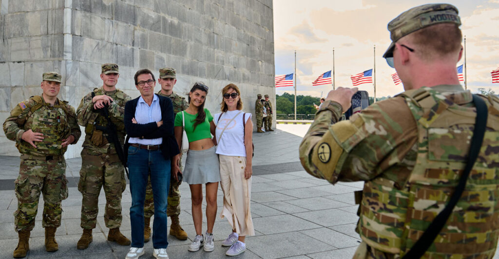 National Guard member takes a photo of some tourists with Guard members at the Washington Monument.