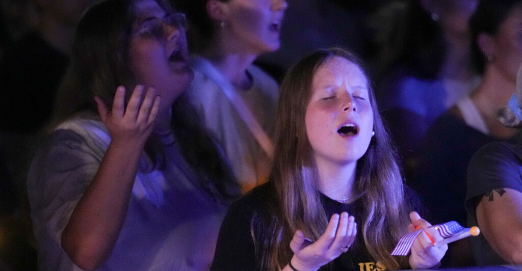 Young woman worship and pray at a vigil for Charlie Kirk.