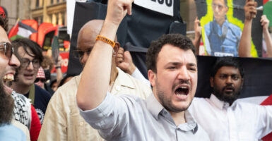Mahmoud Khalil, with arm raised, leads a protest.