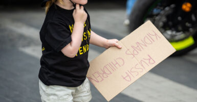 At a rally in Kyiv, Ukraine, on May 26, 2024, a child holds a sign with the handwritten message “Russia kidnaps children.“