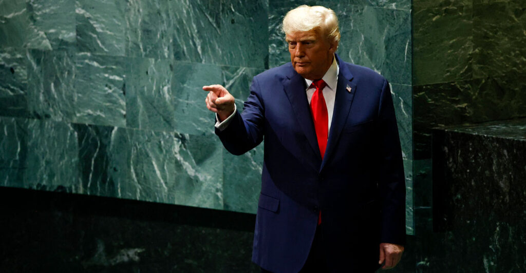 President Donald Trump against green background at U.N., points a finger.