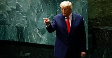 President Donald Trump against green background at U.N., points a finger.