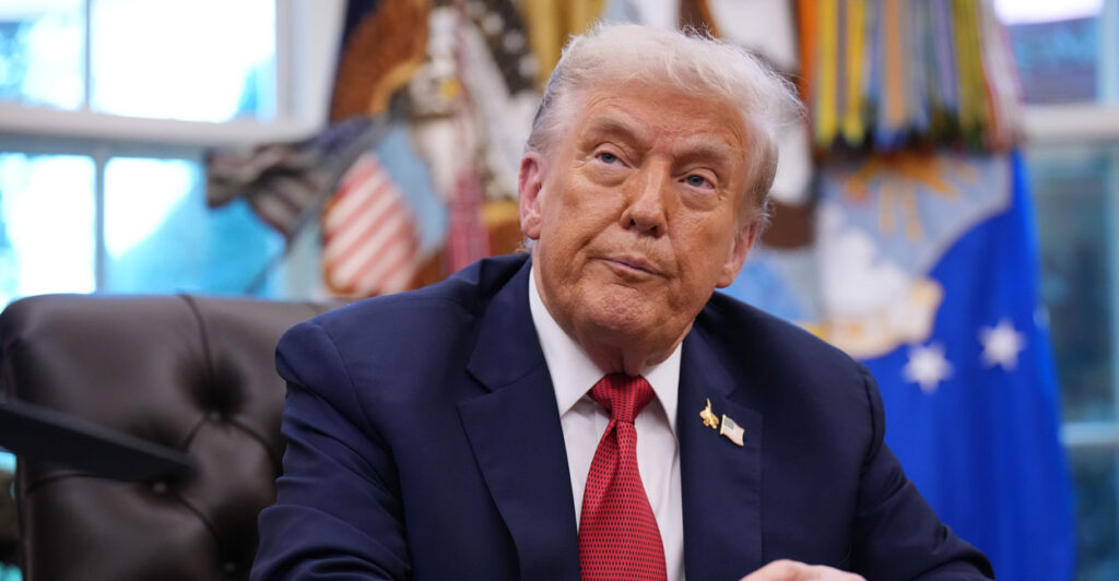 President Trump at his desk in the Oval Office, looking up.