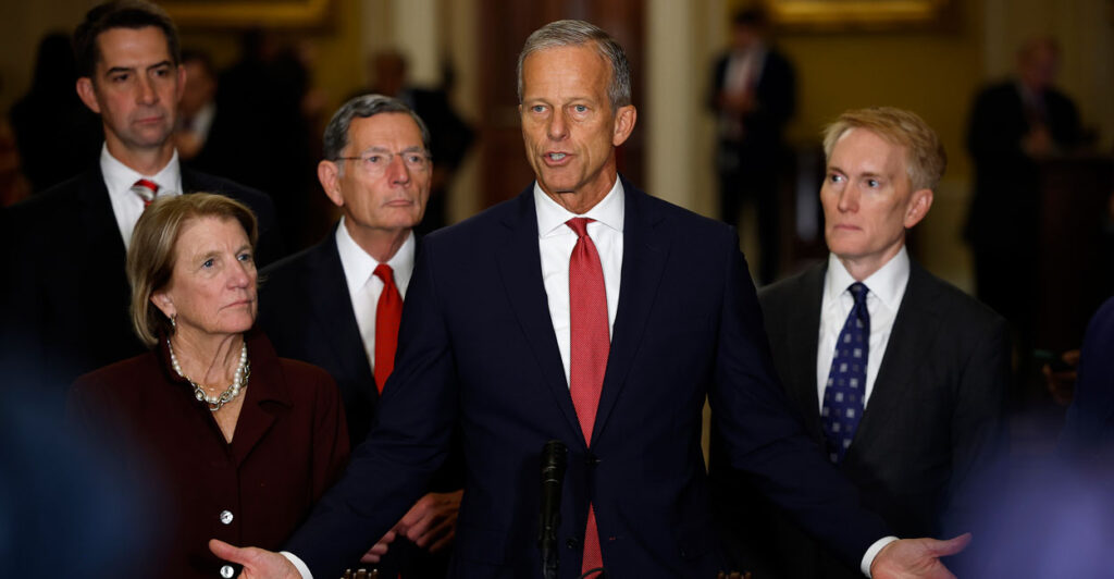 John Thune, arms spread, addresses supporters, surrounded by a group of GOP senators.