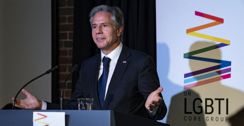 Antony Blinken in front of an LGBTI sign.