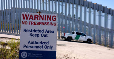 A Border Patrol vehicle is parked at the Border Field State Park with the U.S.-Mexico border wall in the background and a "No Trespassing" sign in view.