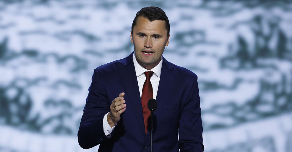 Charlie Kirk gestures in a blue suit