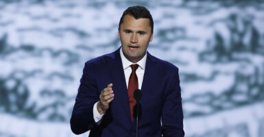 Charlie Kirk gestures in a blue suit