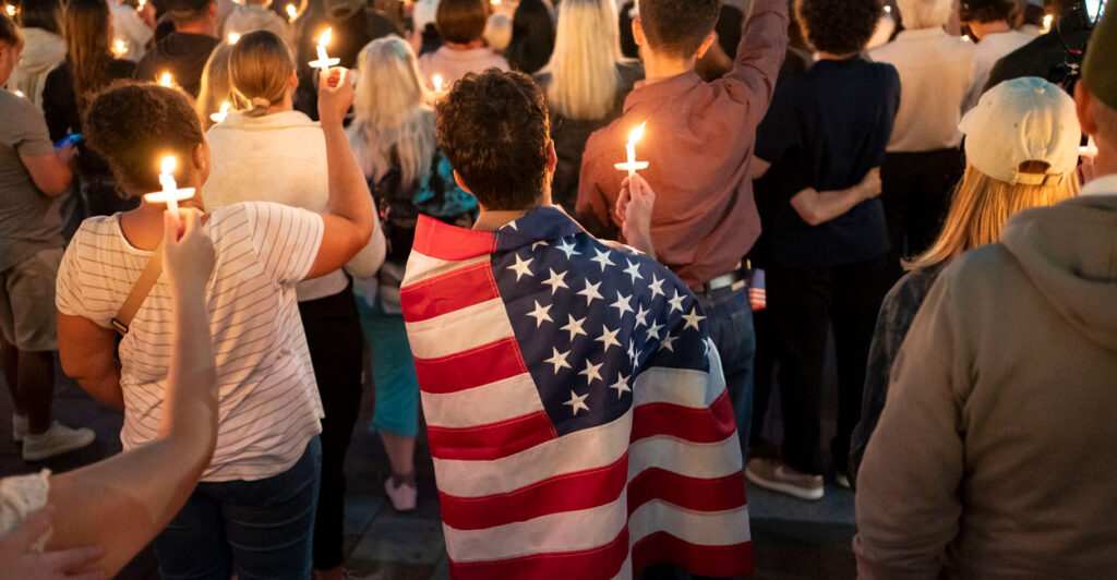 An attendee wears a U.S. flag during a candlelight vigil for Charlie Kirk.
