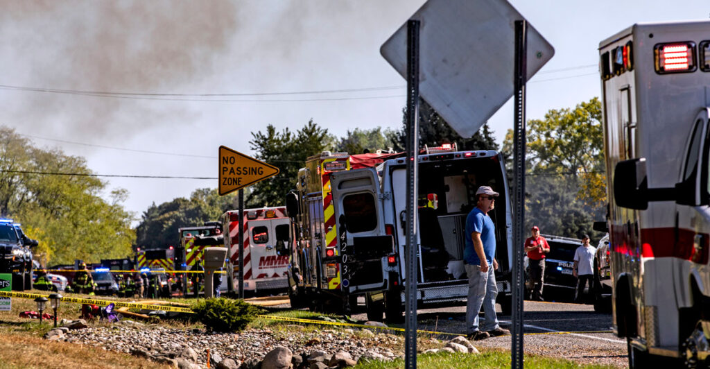 Smoke billows in the sky as ambulances line the street.