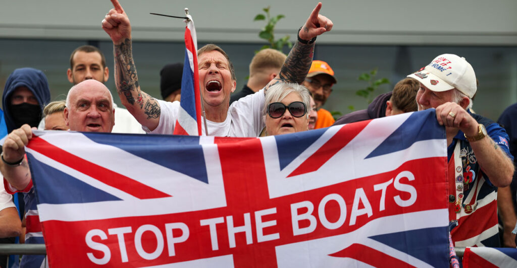 Anti-migrant protesters demonstrate in Falkirk, Scotland, holding up a Union Jack flag that says stop the boats on it