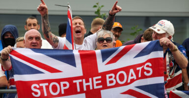Anti-migrant protesters demonstrate in Falkirk, Scotland, holding up a Union Jack flag that says stop the boats on it
