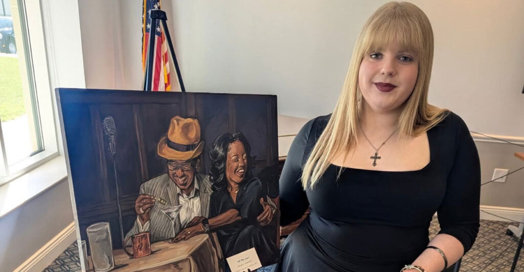 Hayley Chambers stands beside a copy of her winning artwork.