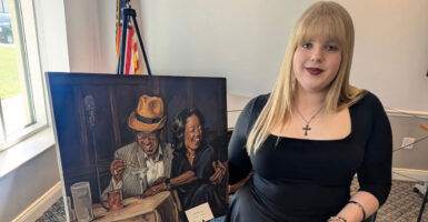 Hayley Chambers stands beside a copy of her winning artwork.