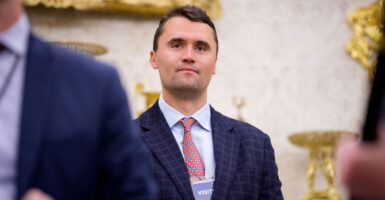 Charlie Kirk smiles while wearing a visitor's badge at the White House.