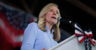 Abigail Spanberger in blue speaks at a podium with American flags