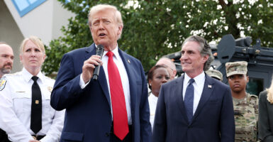 President Trump holds a microphone while standing with law enforcement and Secretary of Interior Doug Burgum.