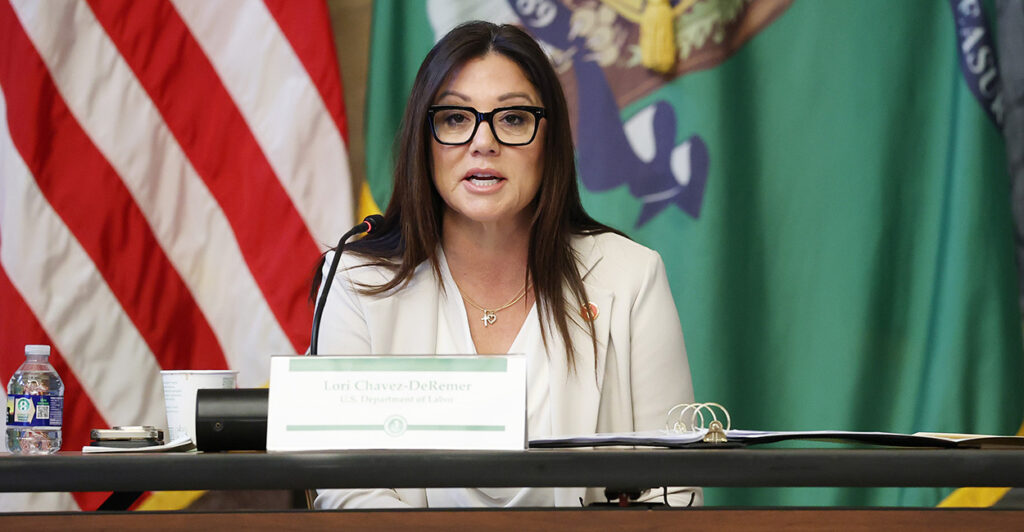 Labor Secretary Lori Chavez-DeRemer in a white suit speaks from behind a desk.
