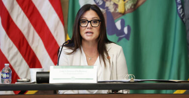 Labor Secretary Lori Chavez-DeRemer in a white suit speaks from behind a desk.