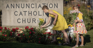 Ruth Pierluissi, 11, left, and Sage Pierluissi, 8, bring flowers to lay in front of Annunciation Catholic Church in Minneapolis, Minn., on Thursday, August 28, 2025.