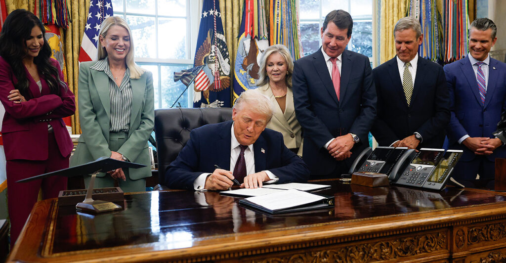 Surrounded by stakeholders, President Donald Trump on Monday signs a memo that authorizes sending members of the National Guard to Memphis, Tenn.
