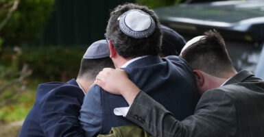 Four people form a circle as they hug each other in grief after their house of worship was attacked.