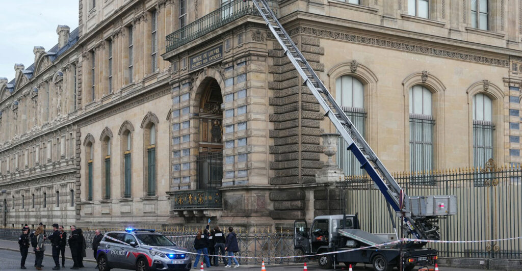 French police officers stand next to a furniture elevator used by robbers to enter the Louvre Museum.