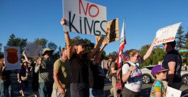 An anti-Donald Trump protesters holds up a sign that says "No Kings" while surrounded by people.