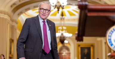 Chuck Schumer stands in the hallway of the U.S. Capitol while looking to his left.