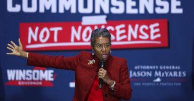 Winsome Earle-Sears stands on a stage holding a microphone in her left hand and extending her right arm out as she talks.