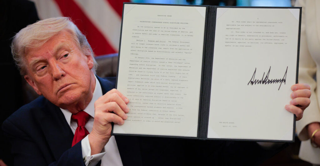Donald Trump holding up a signed executive order.