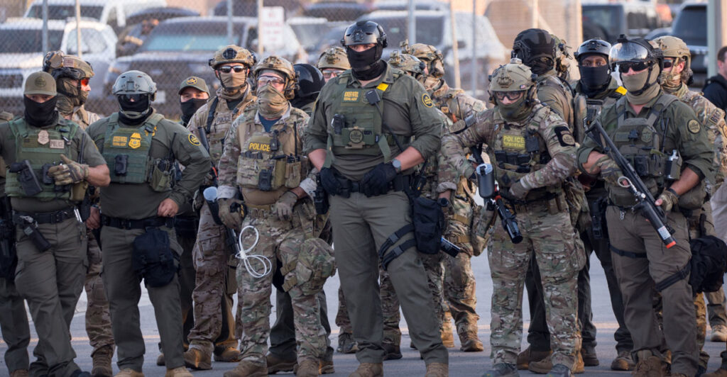 U.S. Immigration and Customs Enforcement agents, Department of Homeland Security personnel, and Border Patrol Commander Gregory Bovino stand together amid a protest outside the ICE processing facility in Broadview, Illinois, on Sept. 27.