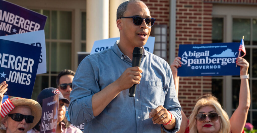 Jay Jones in a blue shirt and sunglasses speaks at a rally.