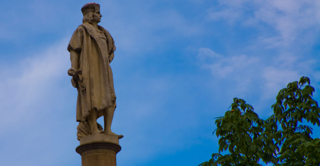 Statue of Christopher Columbs against a blue sky.