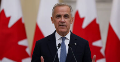 Canadian Prime Minister Mark Carney against a backdrop of Canadian flags.