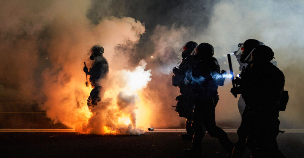 Oregon police in riot gear amid smoke and flames of 2020 riot.
