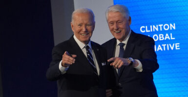 Presidents Joe Biden and Bill Clinton stand side-by-side, smiling and pointing.