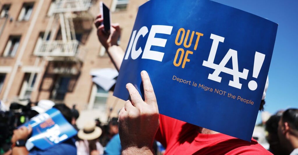 A hand holds a blue sign reading "Ice Out of LA"