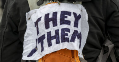 White arm band with black lettering, reading "They Them."