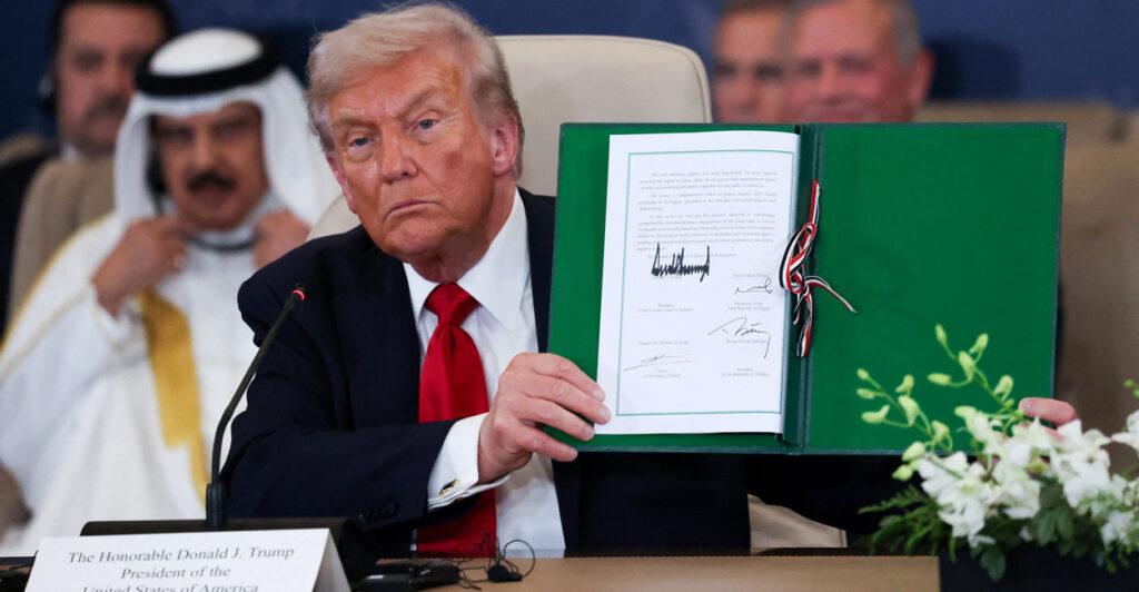 Donald Trump holds up signed Middle East peace deal.