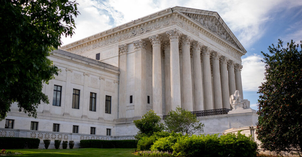 Supreme Court building framed by trees on left and right side of frame.