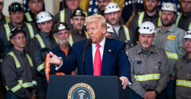 Trump at podium in White House surrounded by coal workers.