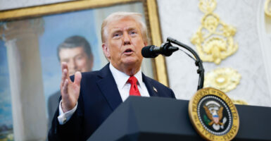President Trumps speaks at a lectern in a dark suit and red tie.