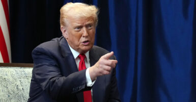 Donald Trump, seated, points.