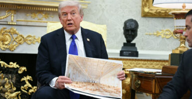 Donald Trump in Oval Office, holding up drawing of White House ballroom.