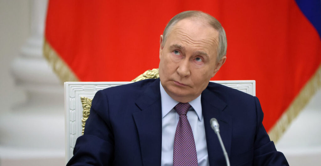 Vladimir Putin, seated, looks up and to his right.