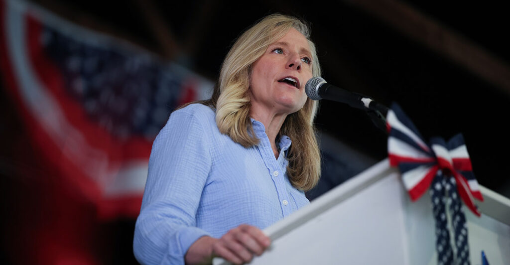 Abigail Spanberger behind a podium with American flags