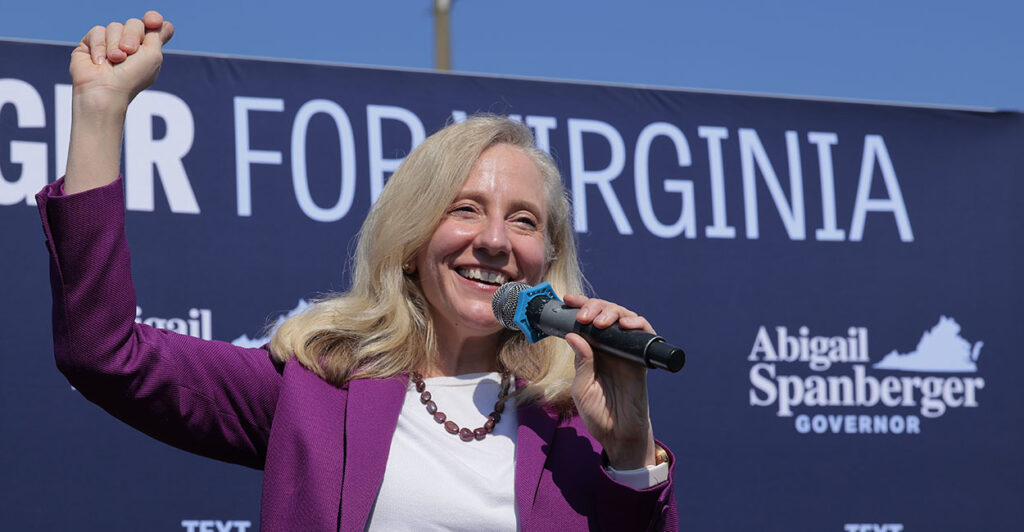 Abigail Spanberger in purple raises her fist
